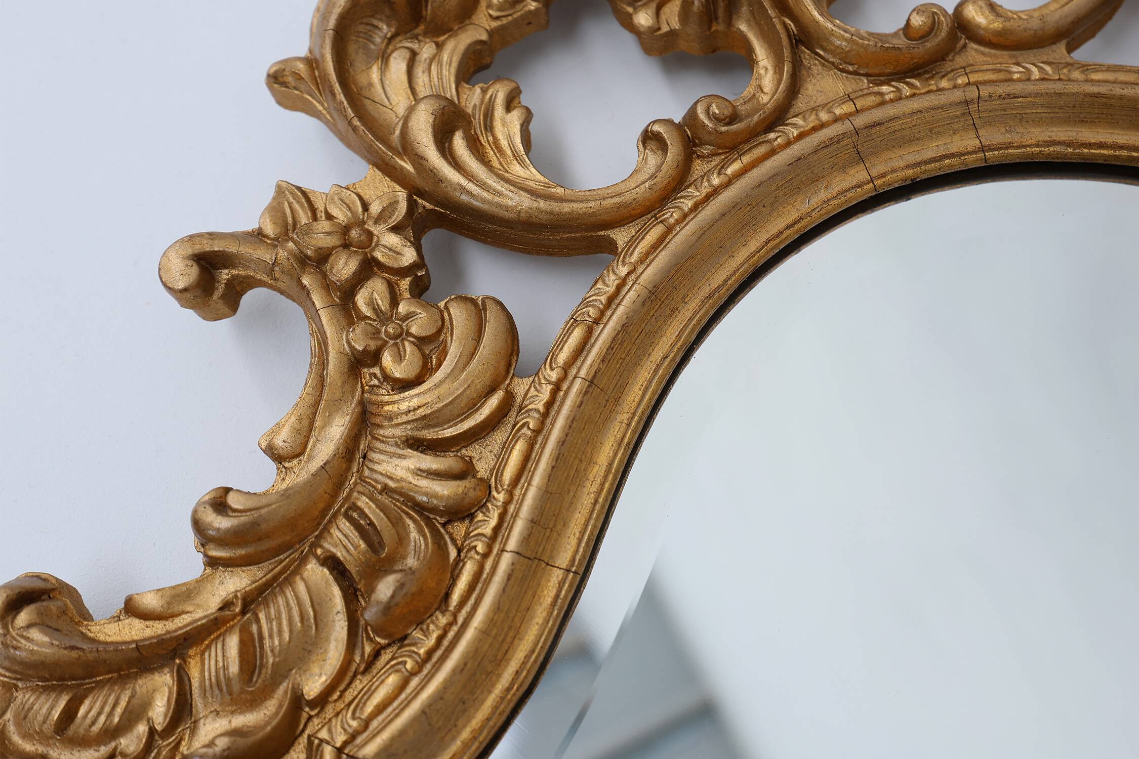French Rococo or Baroque style facet-cut crest mirror in gilded carved wood