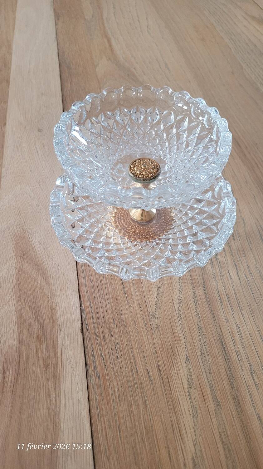Two-tier display stand in cut glass mounted on a gold metal base.