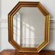 Octagonal gold mirror with copper reflections.