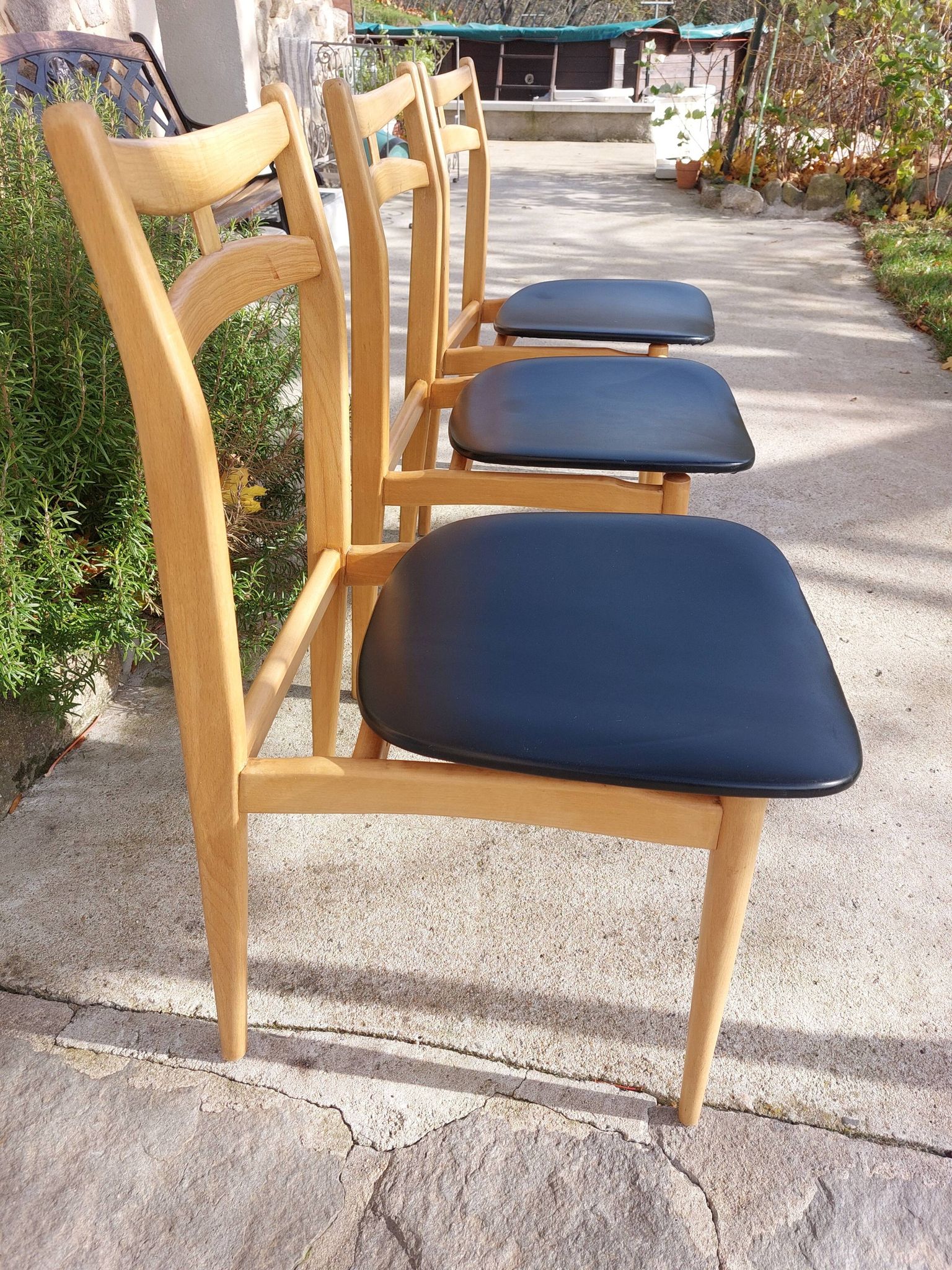 3 Scandinavian style chairs, light wood and black faux leather.
