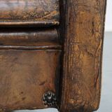 Fauteuil ancien en cuir de mouton sur roulettes et patiné