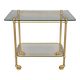 Service trolley on wheels with two glass shelves and a brass frame.