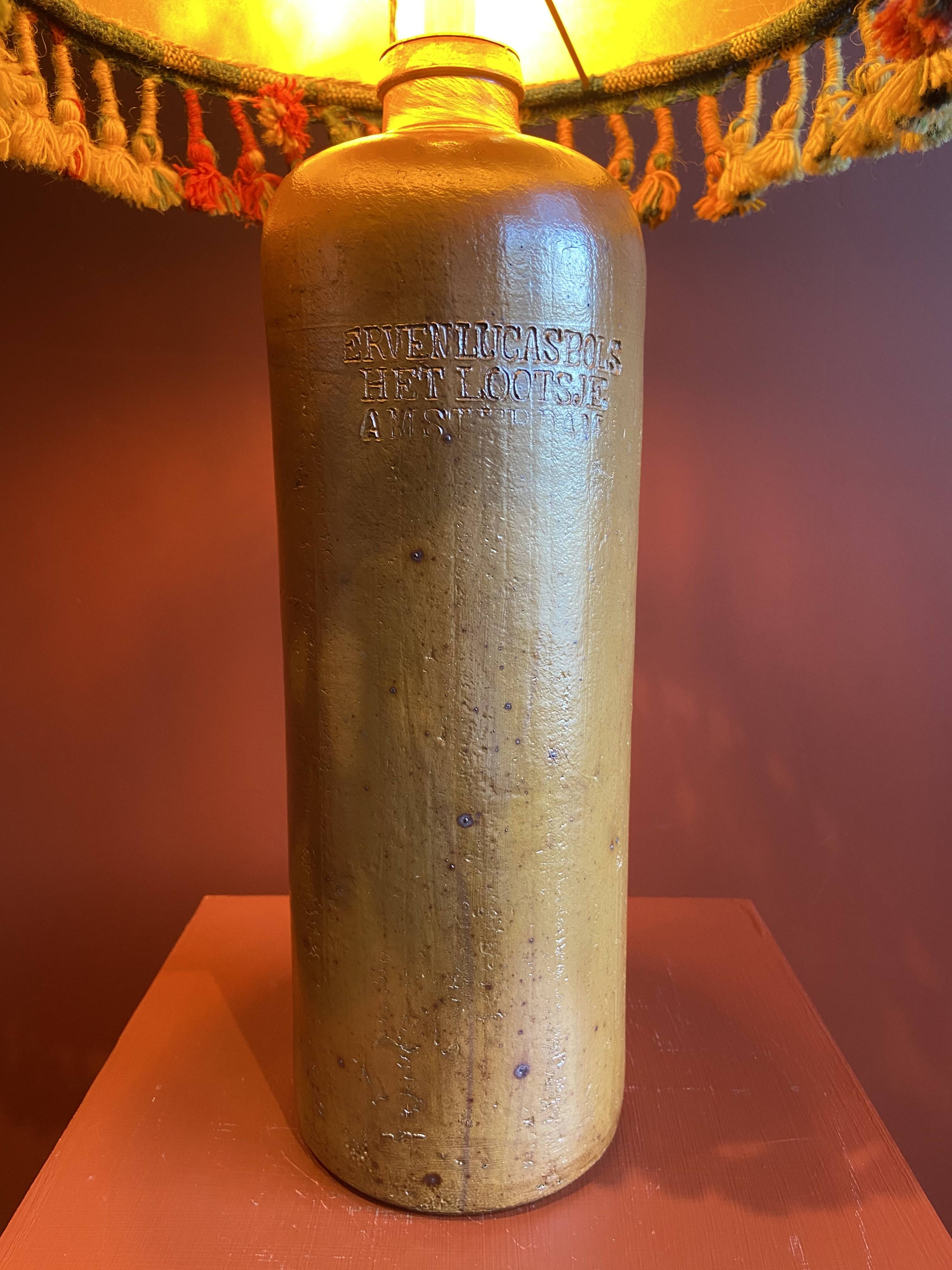 "Stoneware Bottle Lamp" with a multicoloured blue lampshade handwoven in India.