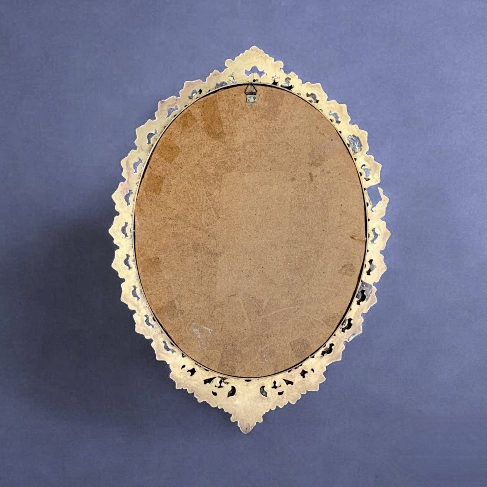 Old oval wall mirror in gilded brass