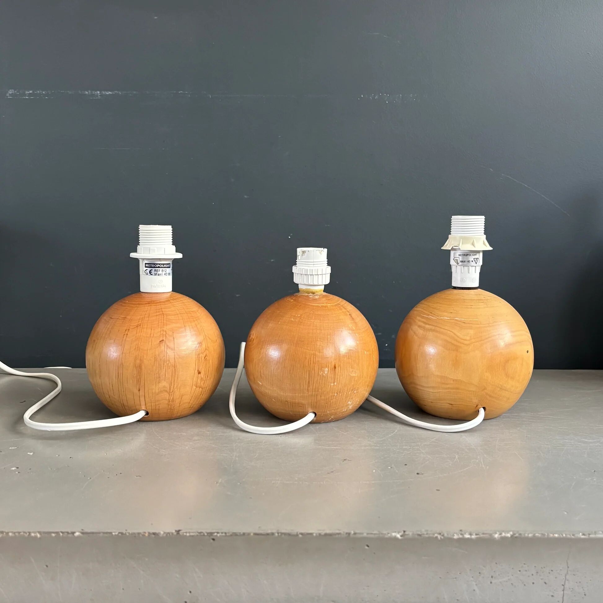 Three wooden ball-shaped lamp stands in light wood.