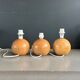 Three wooden ball-shaped lamp stands in light wood.