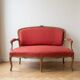 Two-seater Louis XV style sofa in red fabric.
