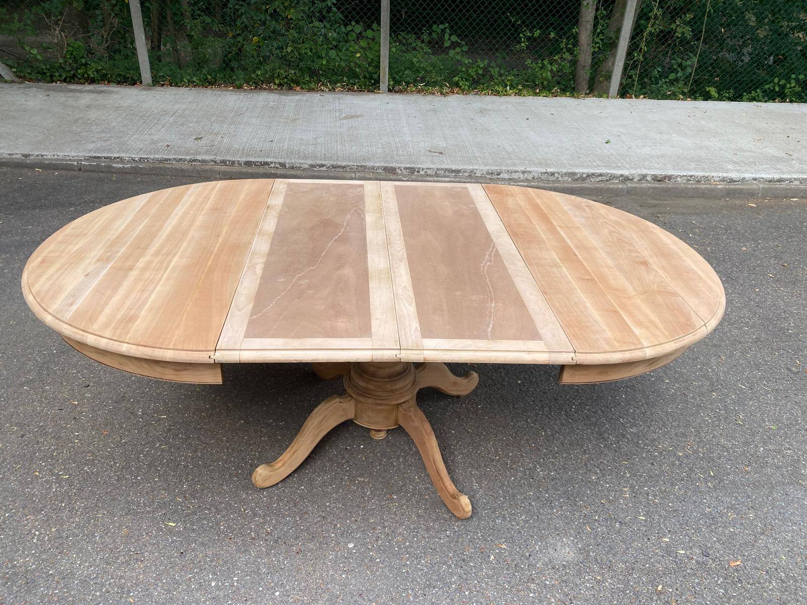Round dining table with a central pedestal, extendable, stripped in solid walnut with 2 extensions.
