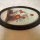 Oval painting of a bouquet of flowers, oil on panel.