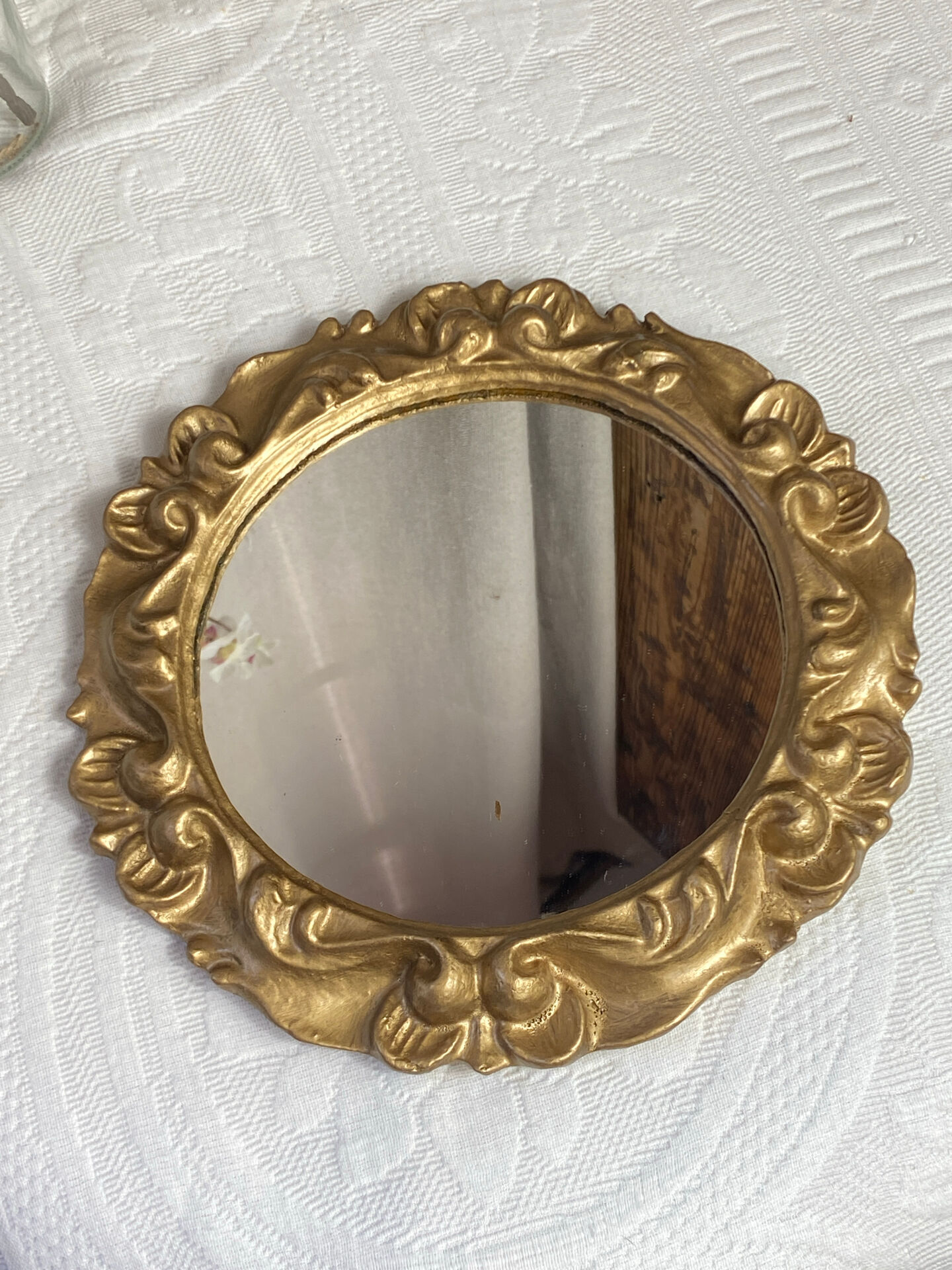 Round wooden mirror in golden colour.