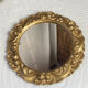 Round wooden mirror in golden colour.