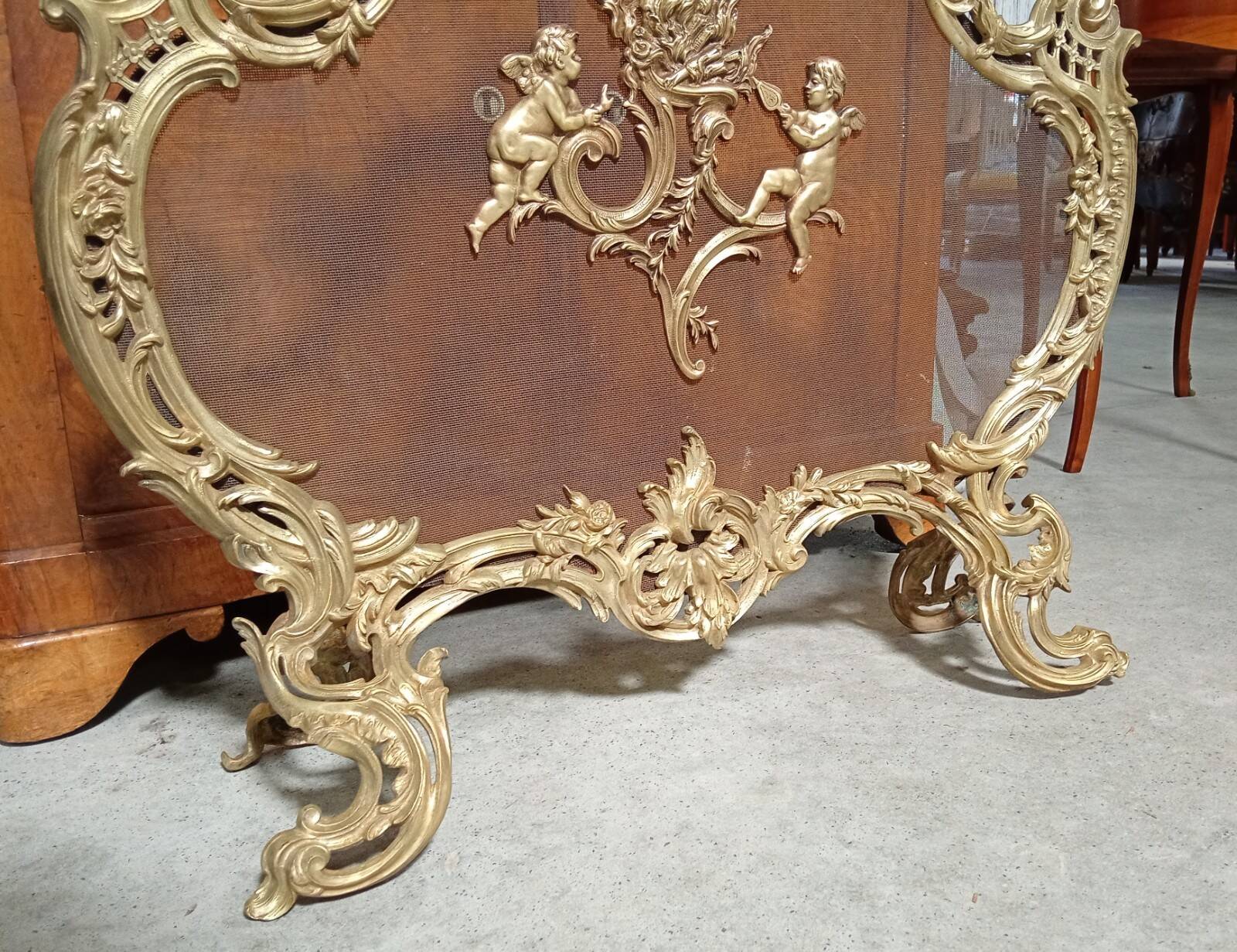 Large gilded bronze fireplace screen decorated with putti and rocaille motifs.