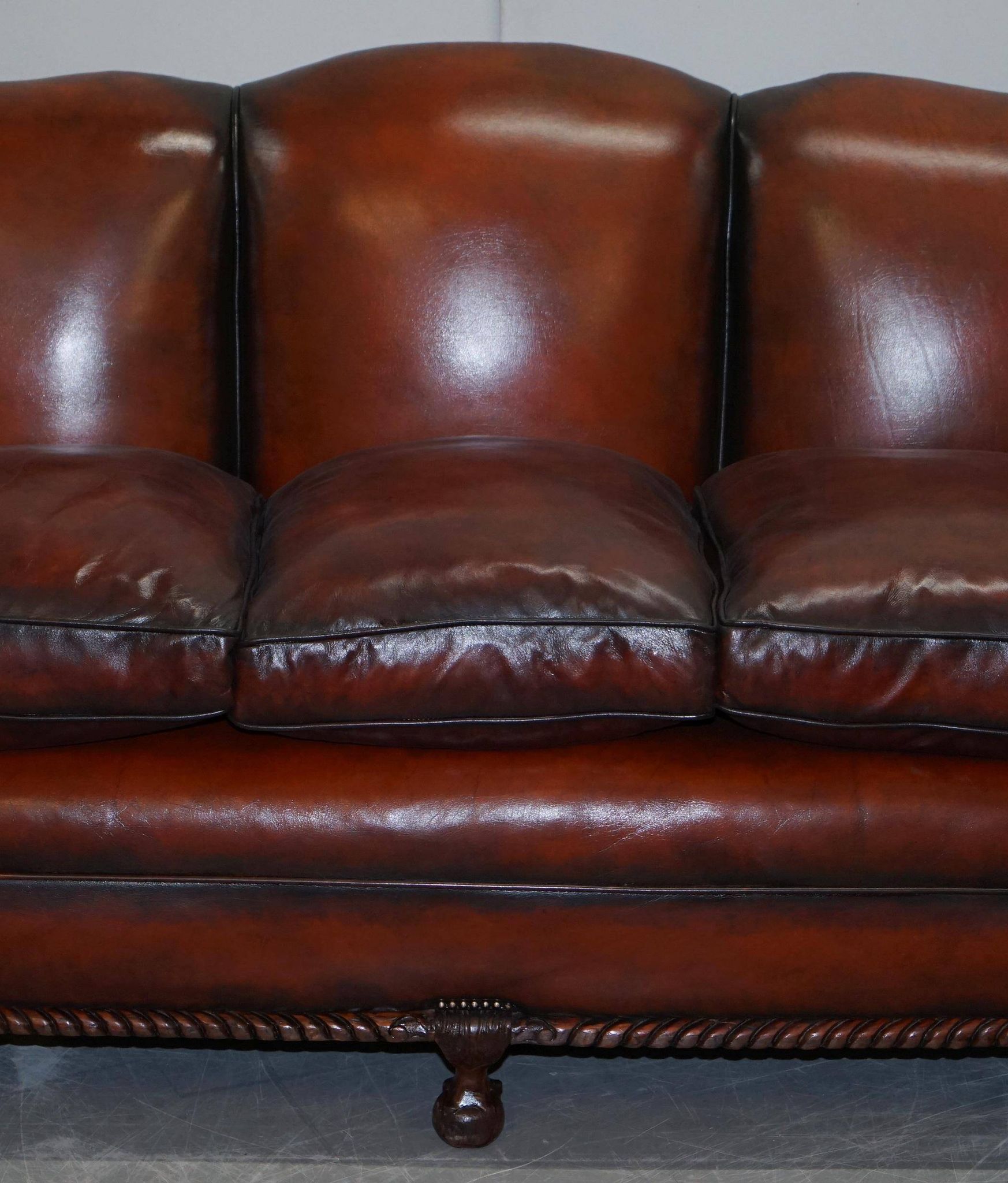 Restored Victorian sofa in leather with claw feet and feather cushions.