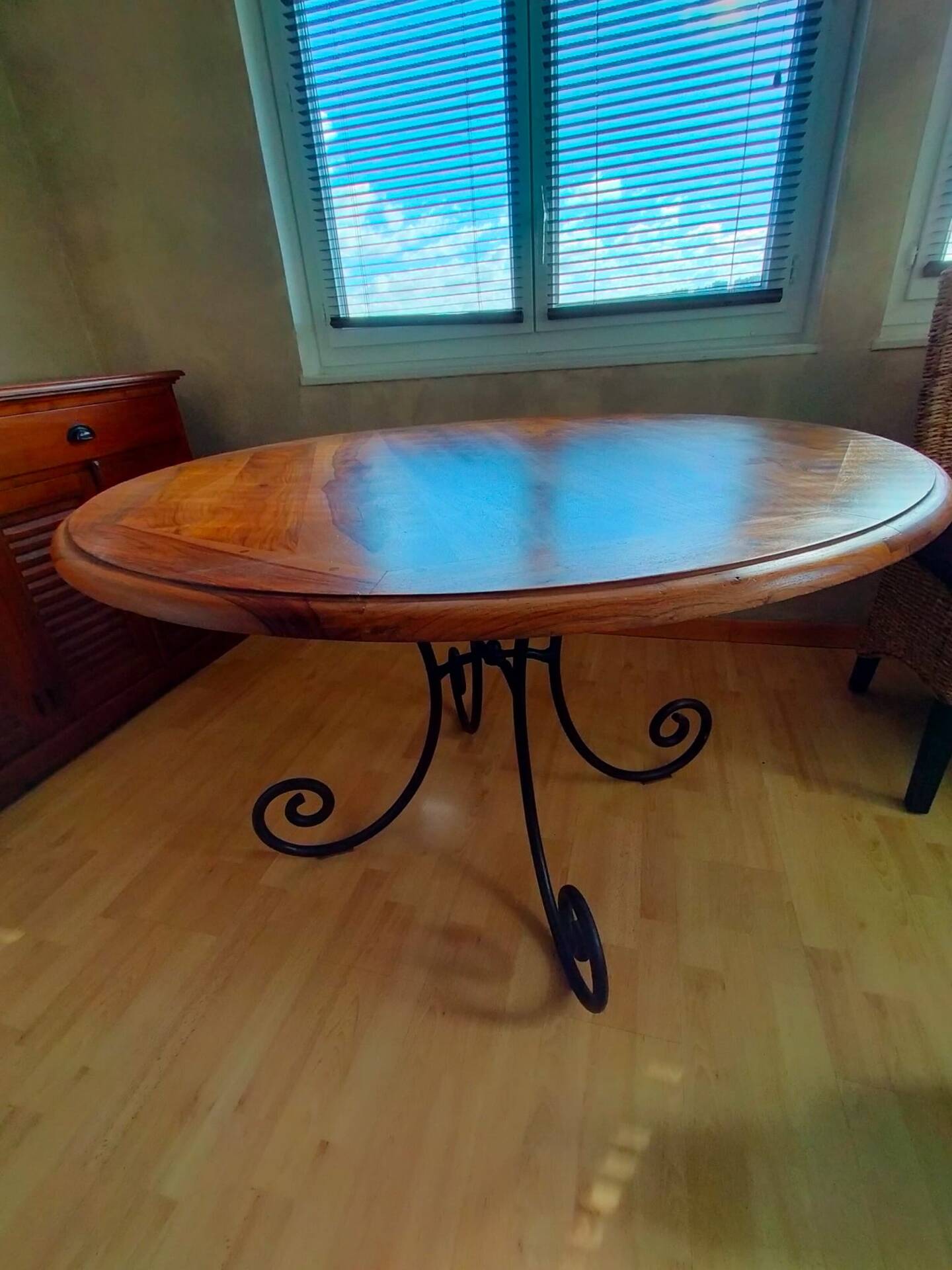 Round wooden table with wrought iron legs.