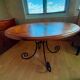 Round wooden table with wrought iron legs.