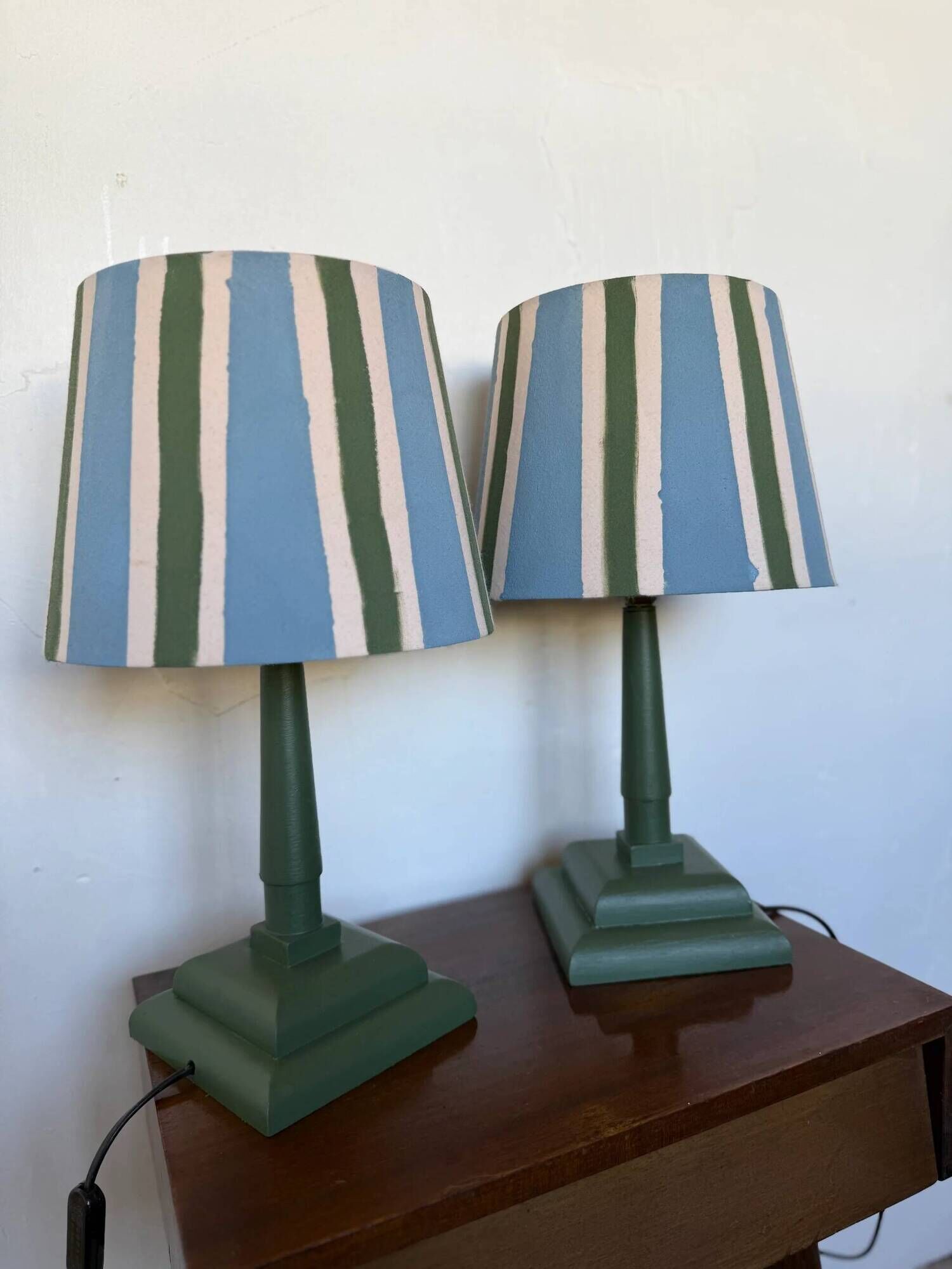 Pair of vintage wooden lamps with their striped beige, blue, and green shades.