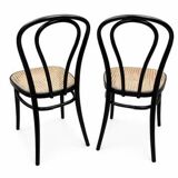 Pair of black curved wooden bistro chairs with caning in Thonet style.