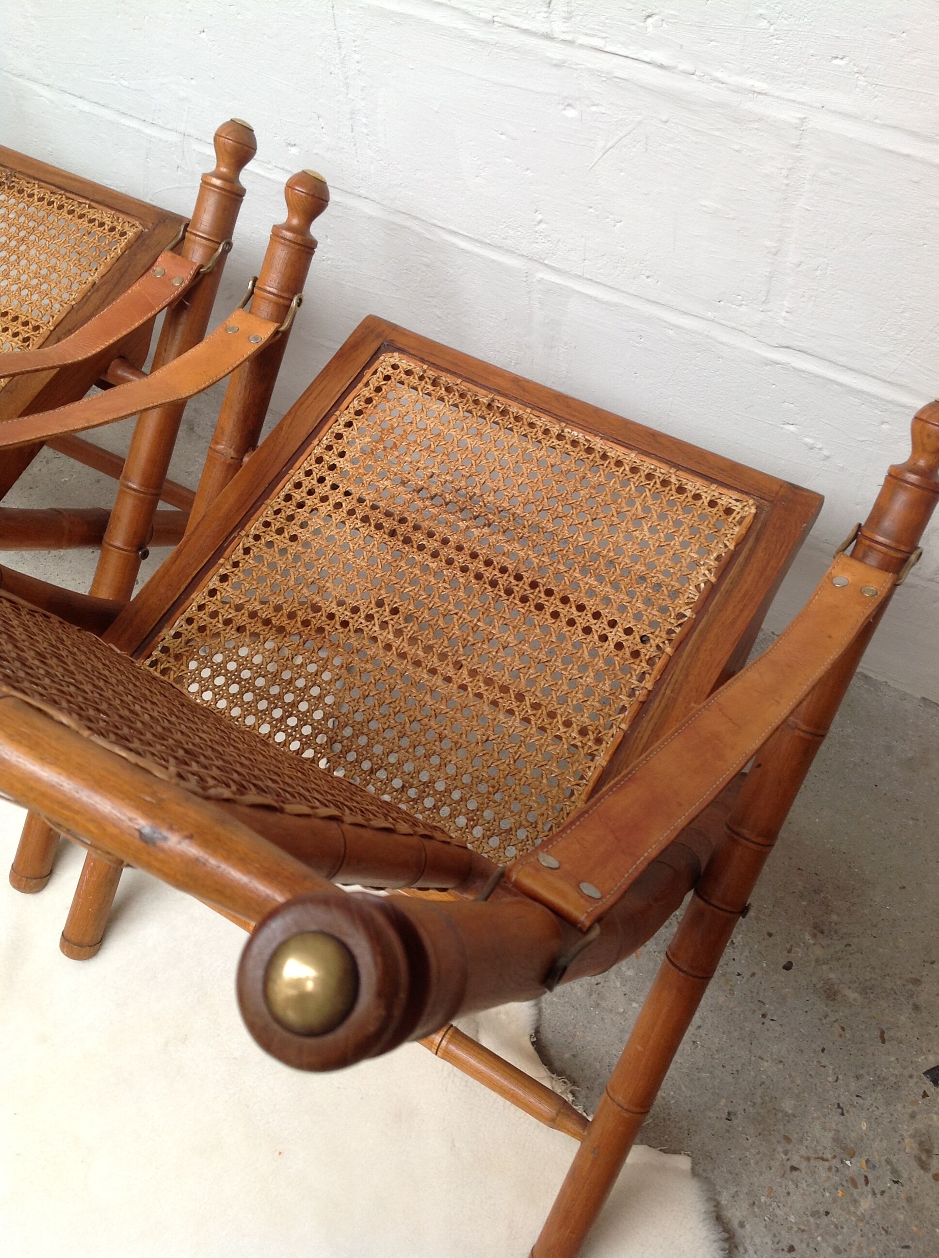 Pair of folding chairs in bamboo and caning, leather and brass