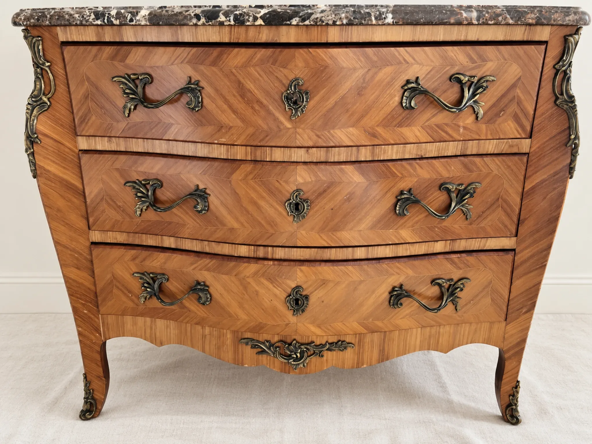 Curved Louis XV style commode in marquetry, veined marble and ornamentation.