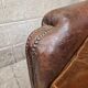 Antique club chair in patinated brown leather, early 20th century English style.