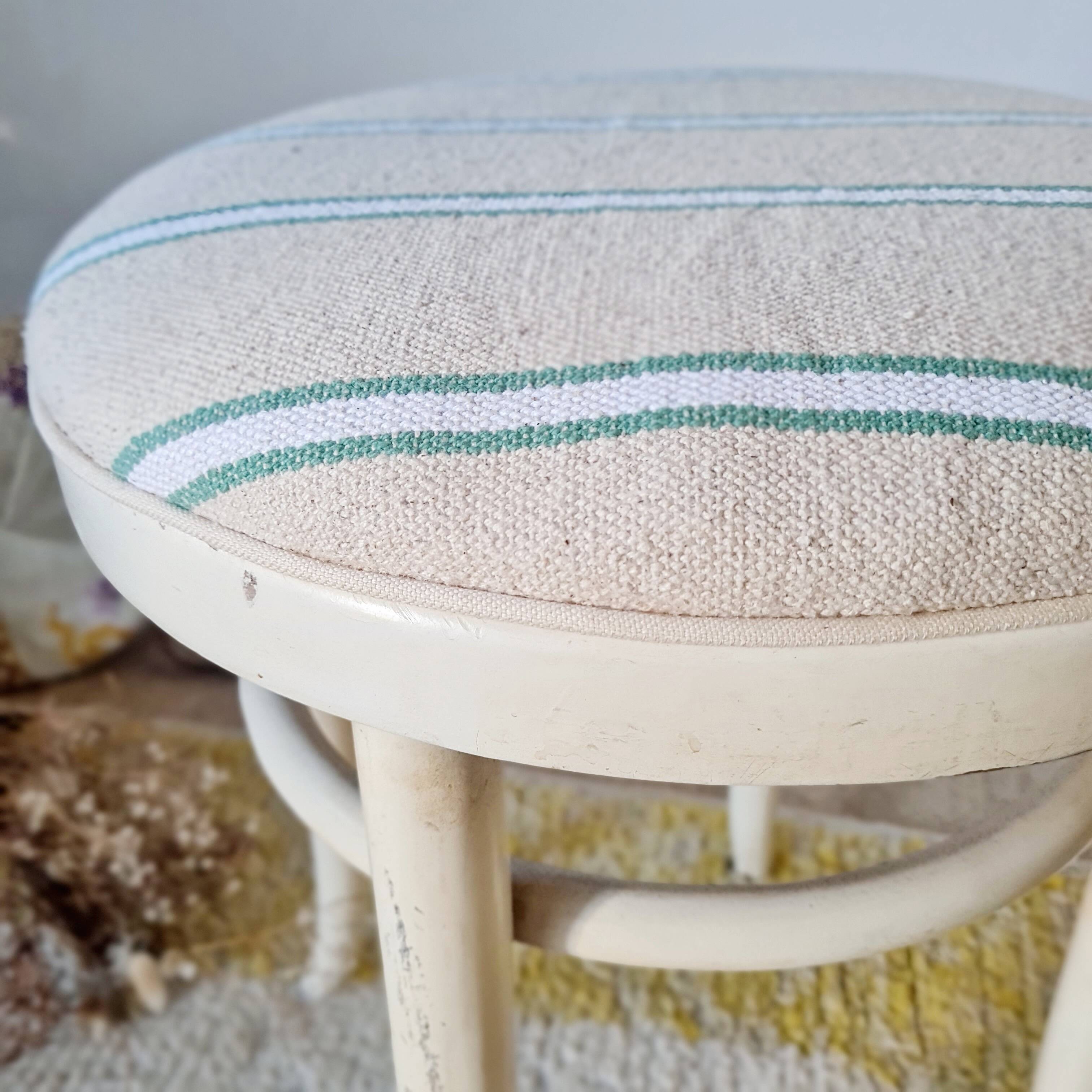 Antique stool with a wooden frame and a cream and green striped fabric seat.