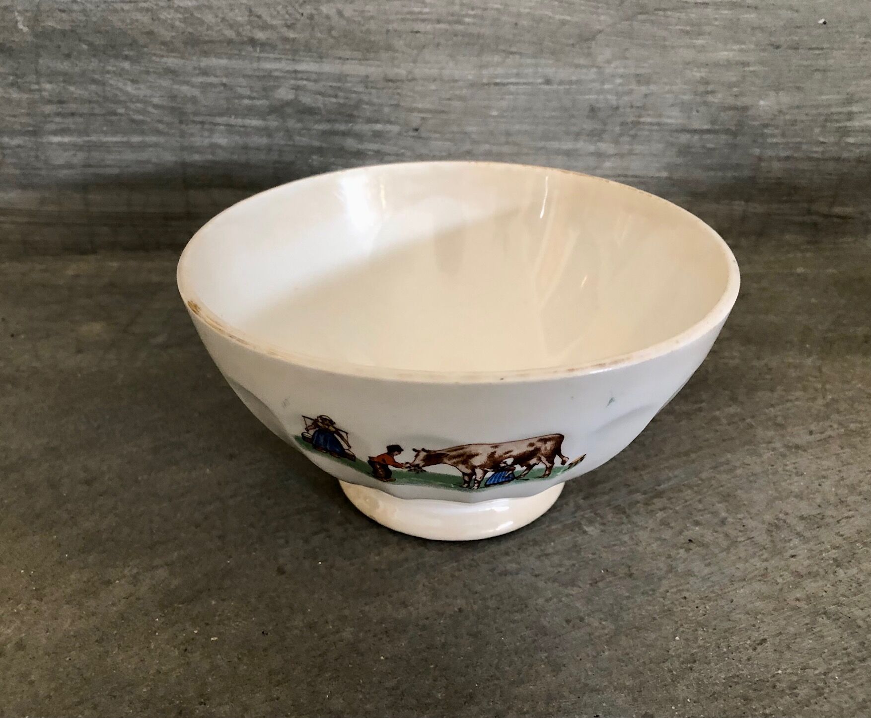 Old bowl decorated with a farmer and her cow
