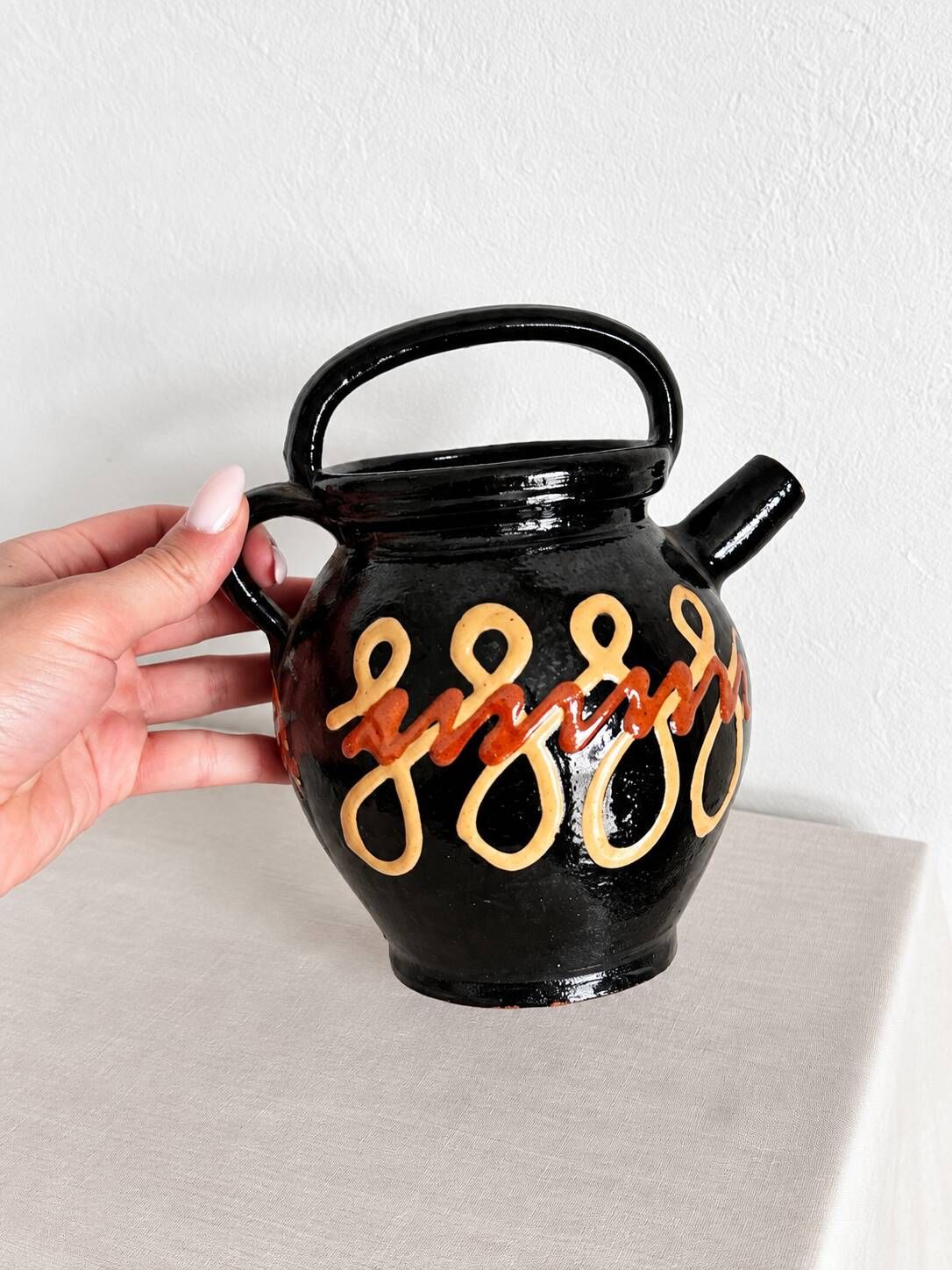 Old vase in glossy black ceramic, vintage exterior decoration.