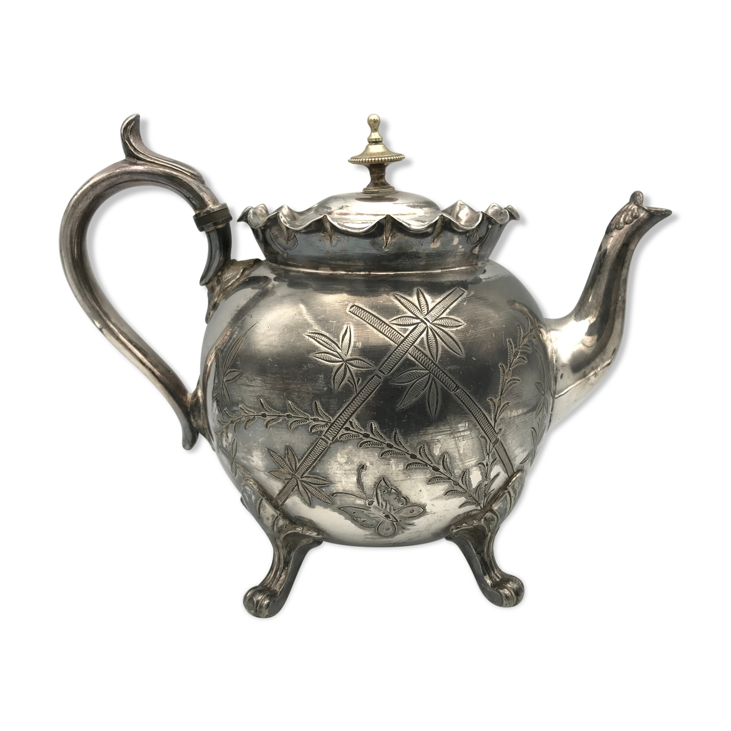 Old teapot pourer in silver metal decorated with foliage and butterflies