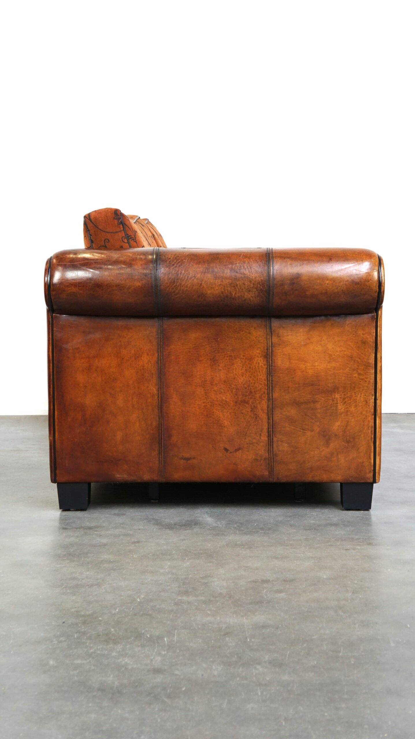 Canapé en cuir de mouton 2,5 places, luxueux et confortable, avec des coussins en tissu.