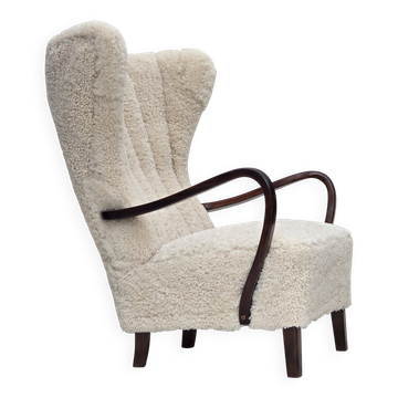 Fauteuil danois à dossier haut des années 1960, en véritable peau de mouton, retapissé.
