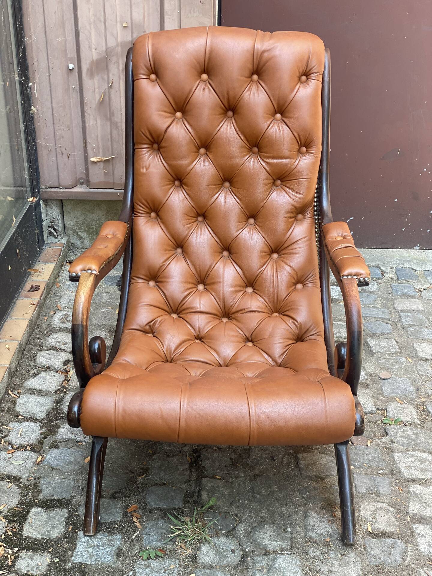 Chesterfield armchair in leather and carved solid wood