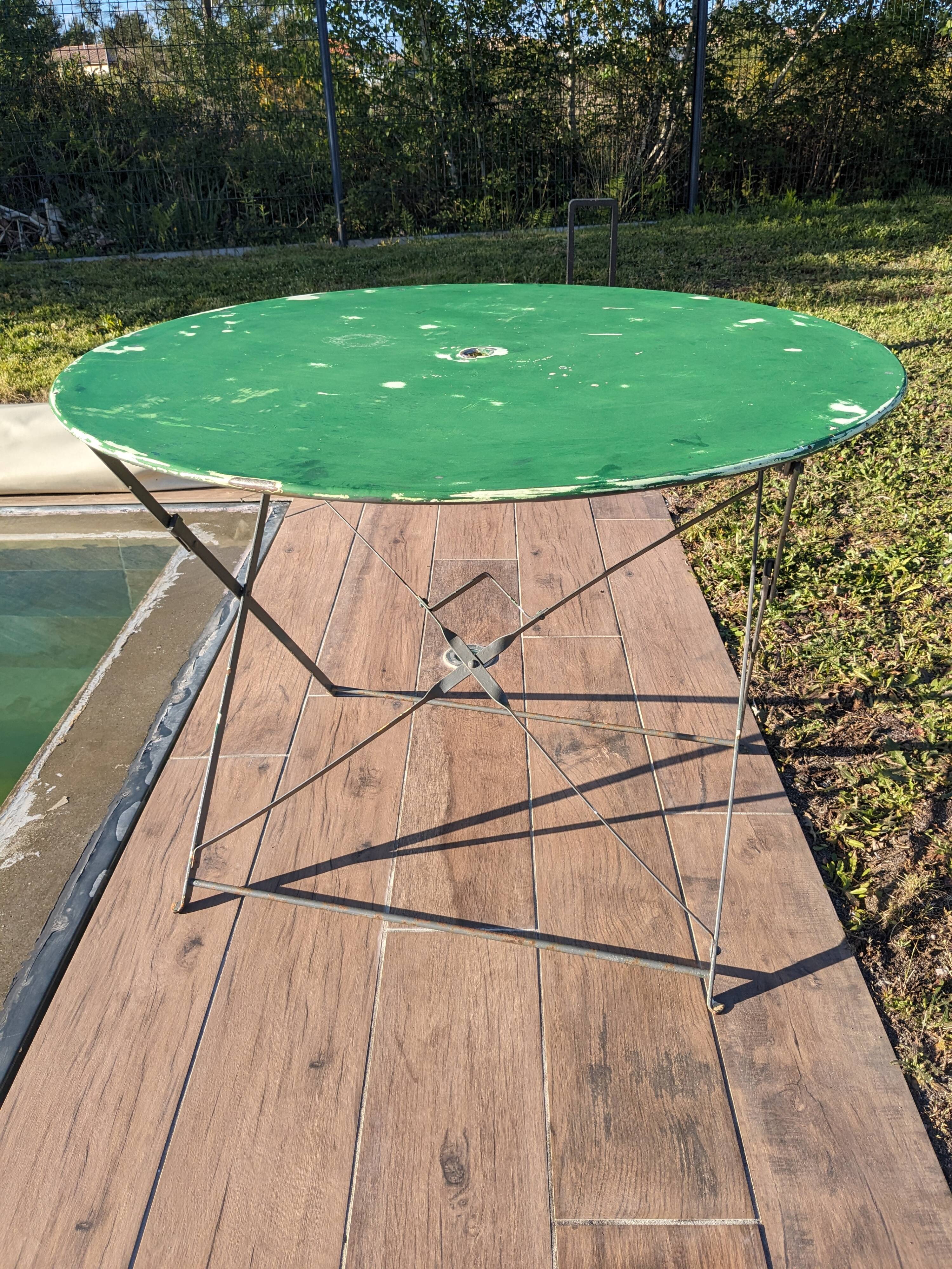 Antique round folding garden table with a green patina.