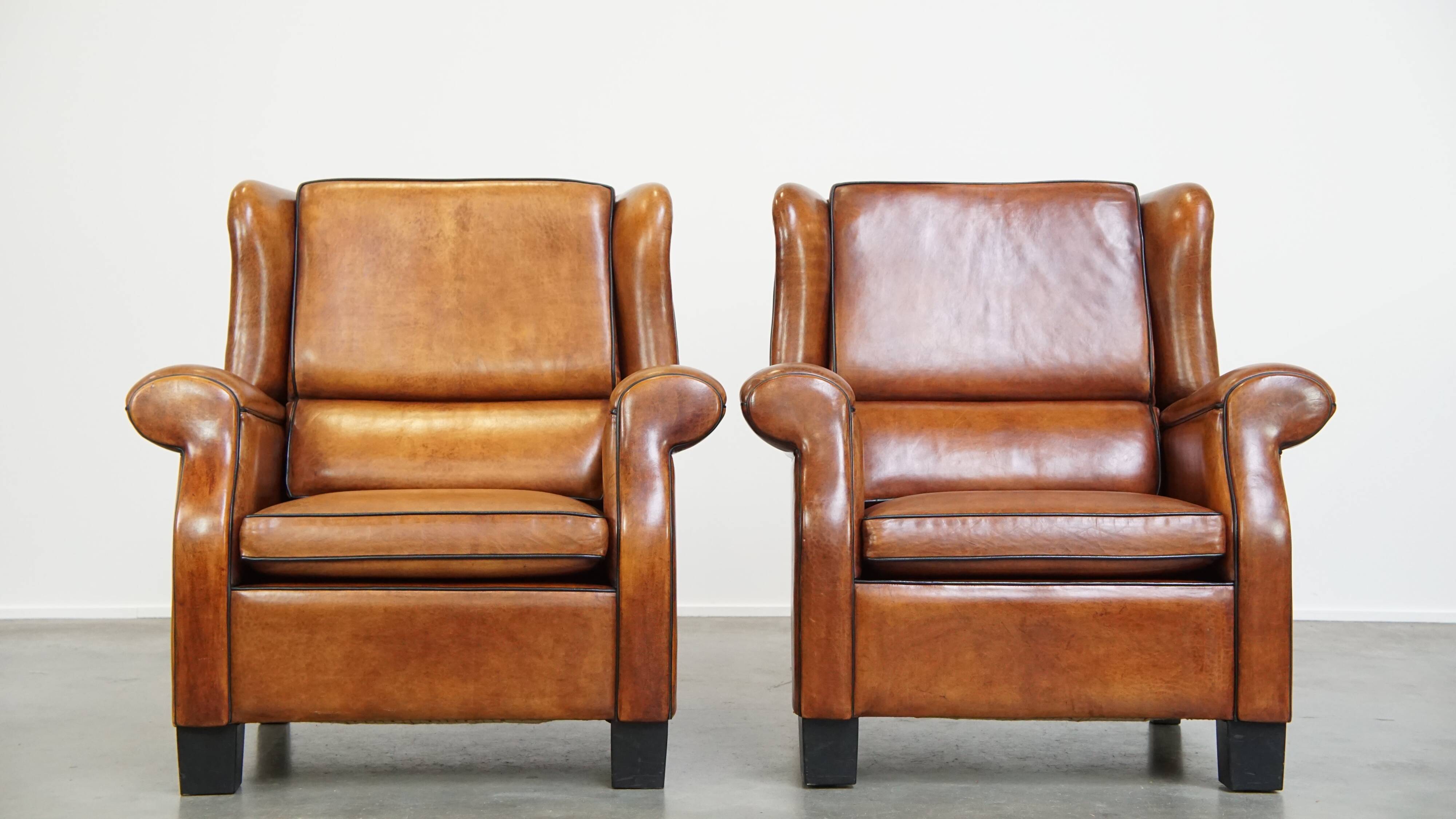 Set of 2 very comfortable large sheepskin armchairs elegantly finished with black piping