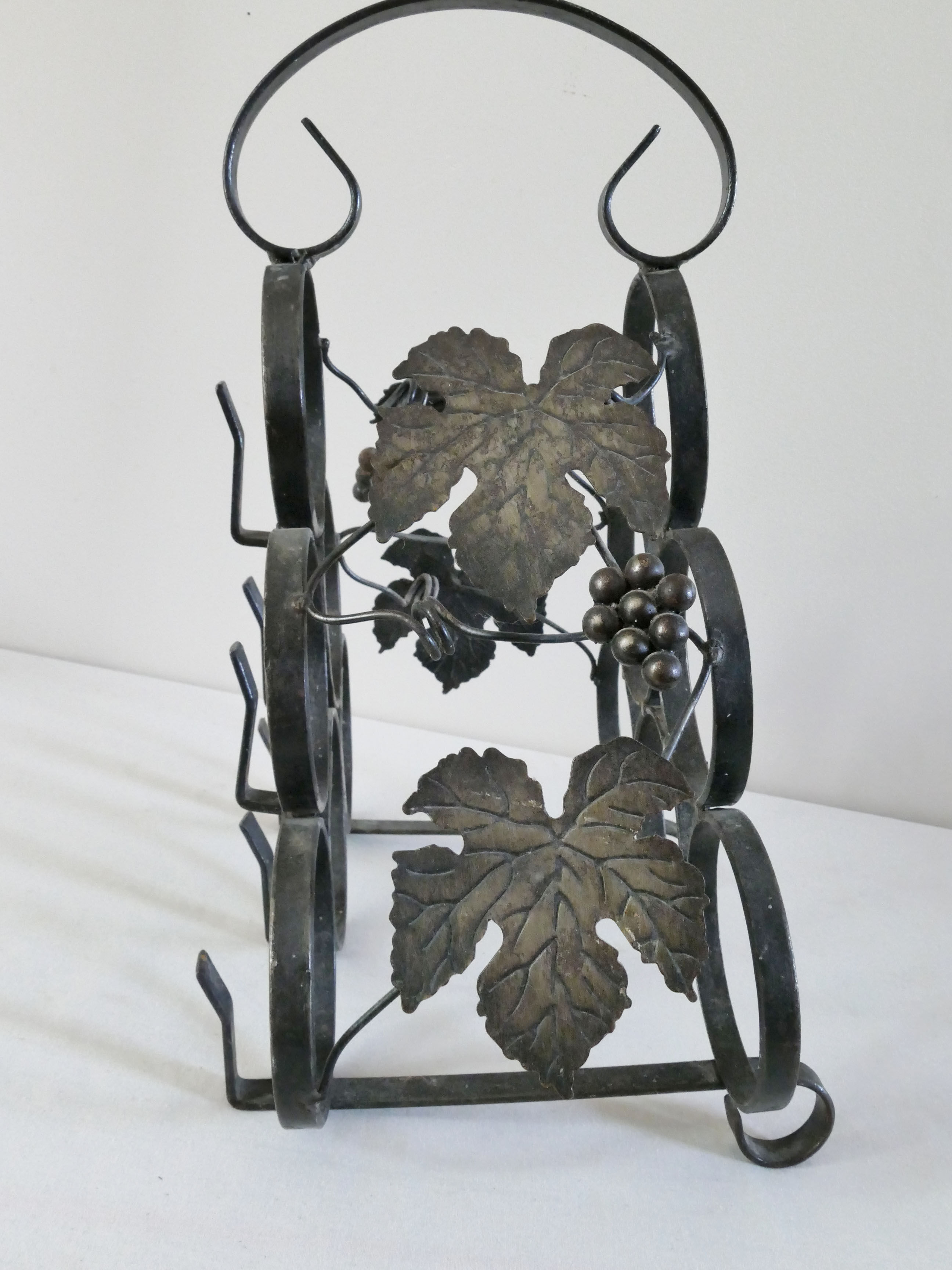 Vintage black wrought iron bottle holder decorated with vine leaves