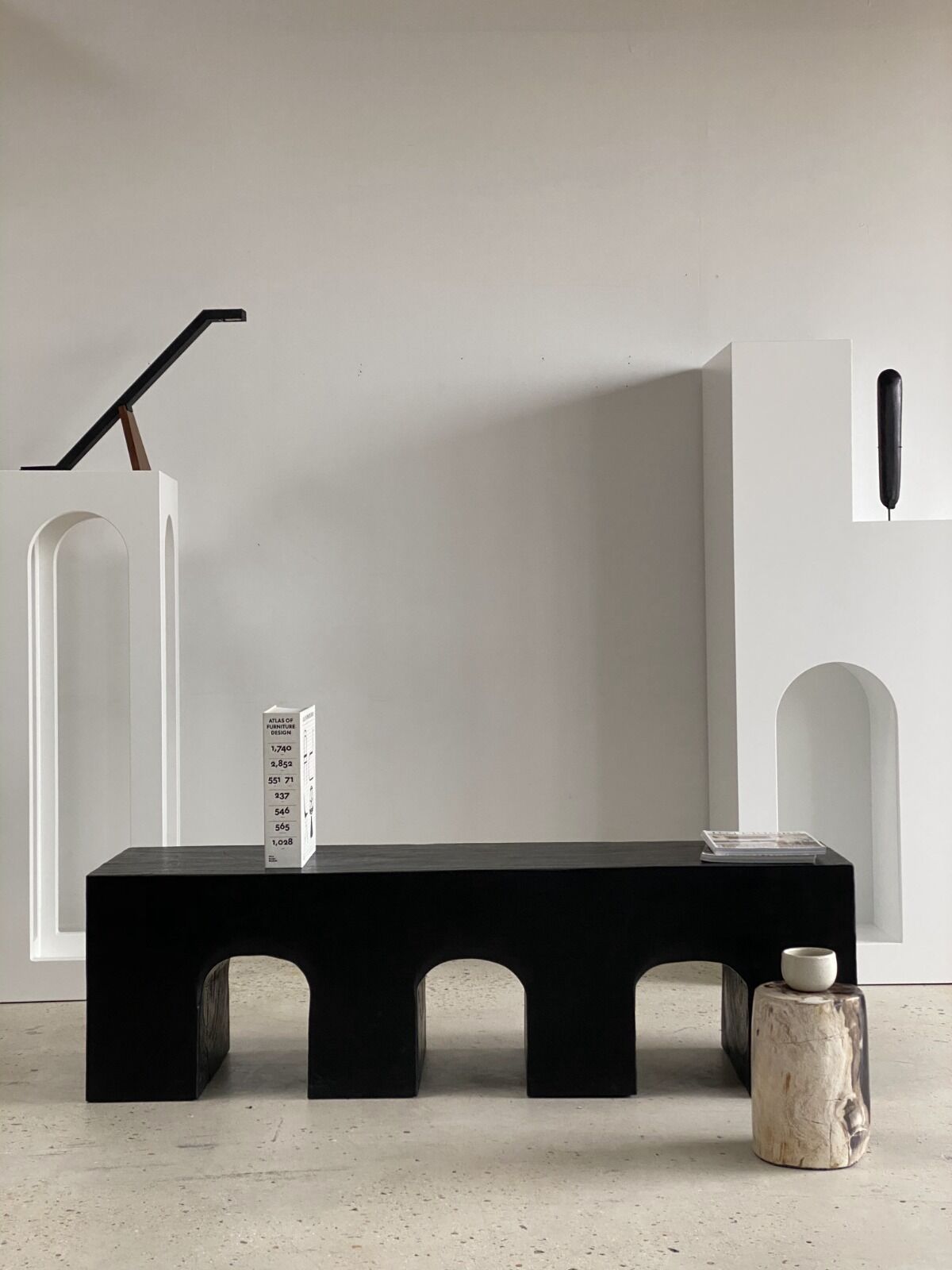 Black solid monoxyl wood bench carved into 3 arches