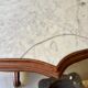 Table with a carved wooden frame and grey marble top on wheels, measuring 130 x 82 cm.