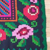 Handwoven colorful Romanian carpet, green and black background with gorgeous colorful flowers