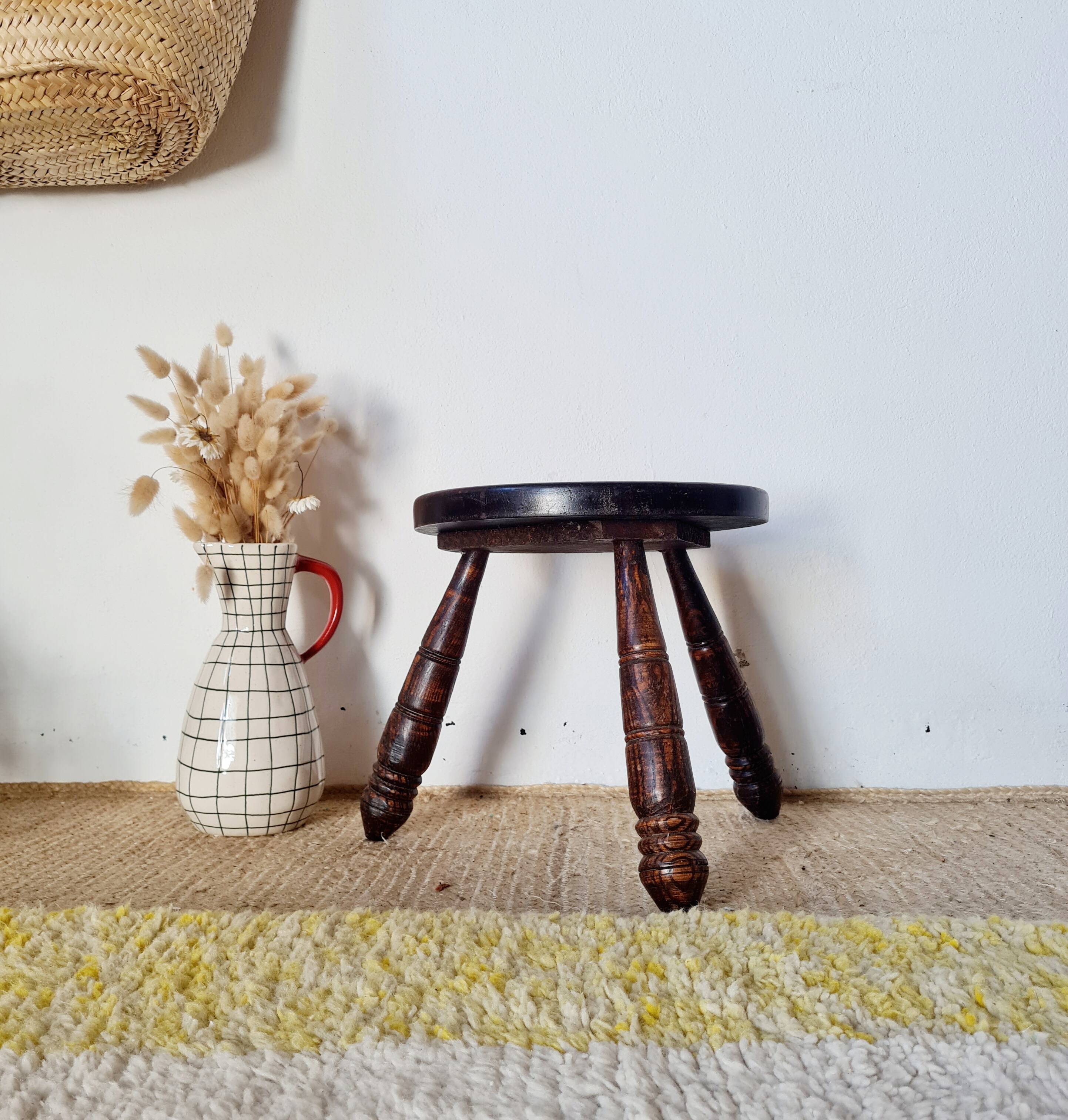Small brutalist tripod stool made of turned wood.