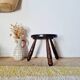 Small brutalist tripod stool made of turned wood.