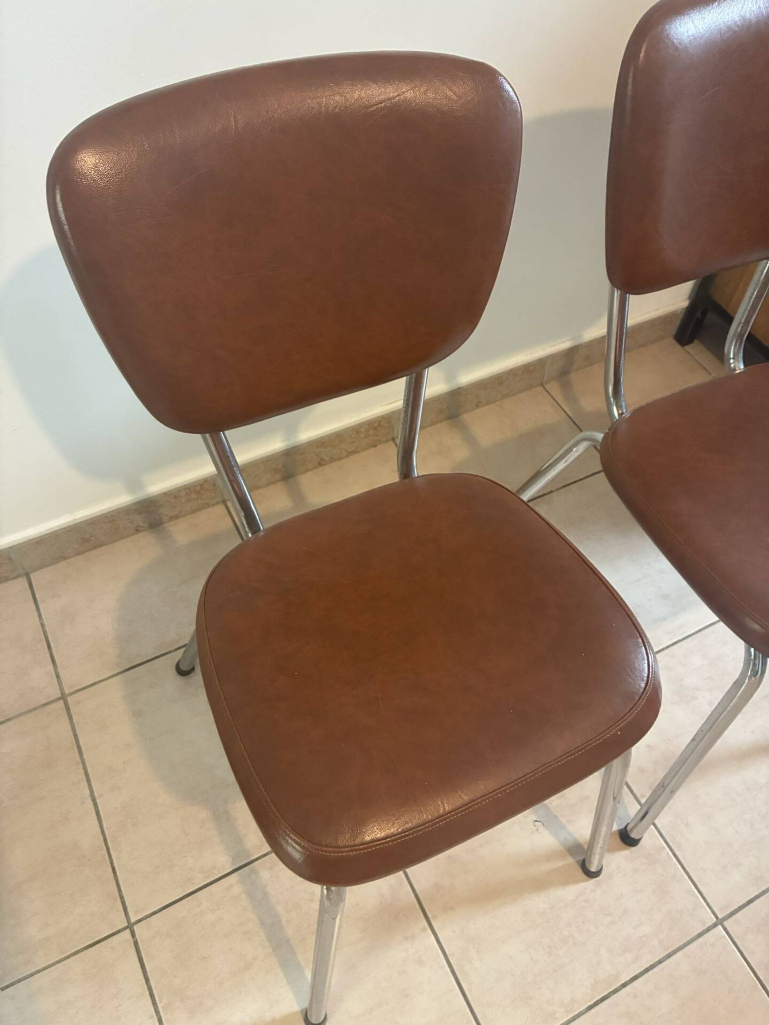 Two brown faux leather chairs.
