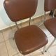 Two brown faux leather chairs.