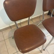 Two brown faux leather chairs.