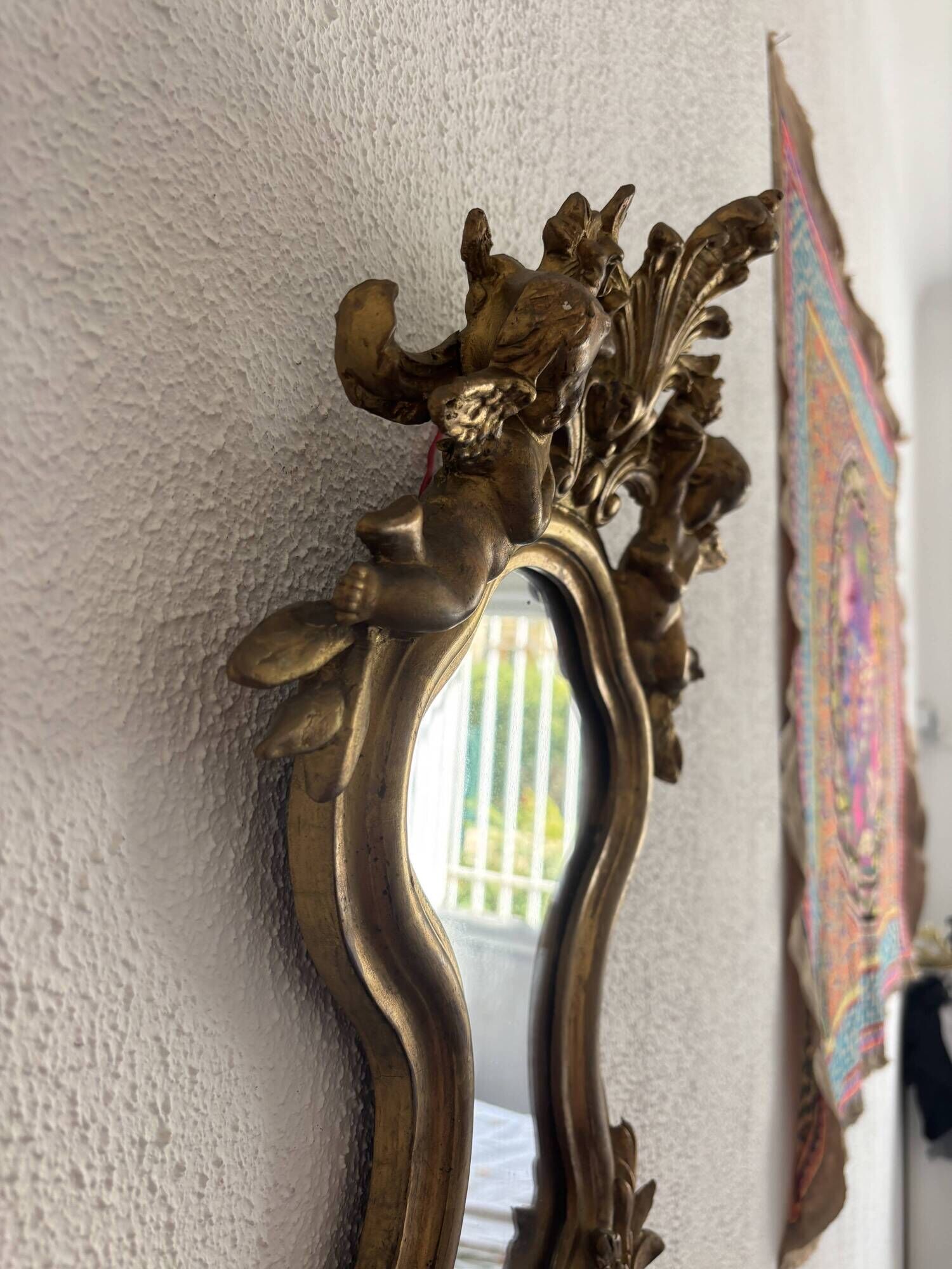 Antique rococo mirror with putti, gilded carved wood and stucco frame, 19th century.