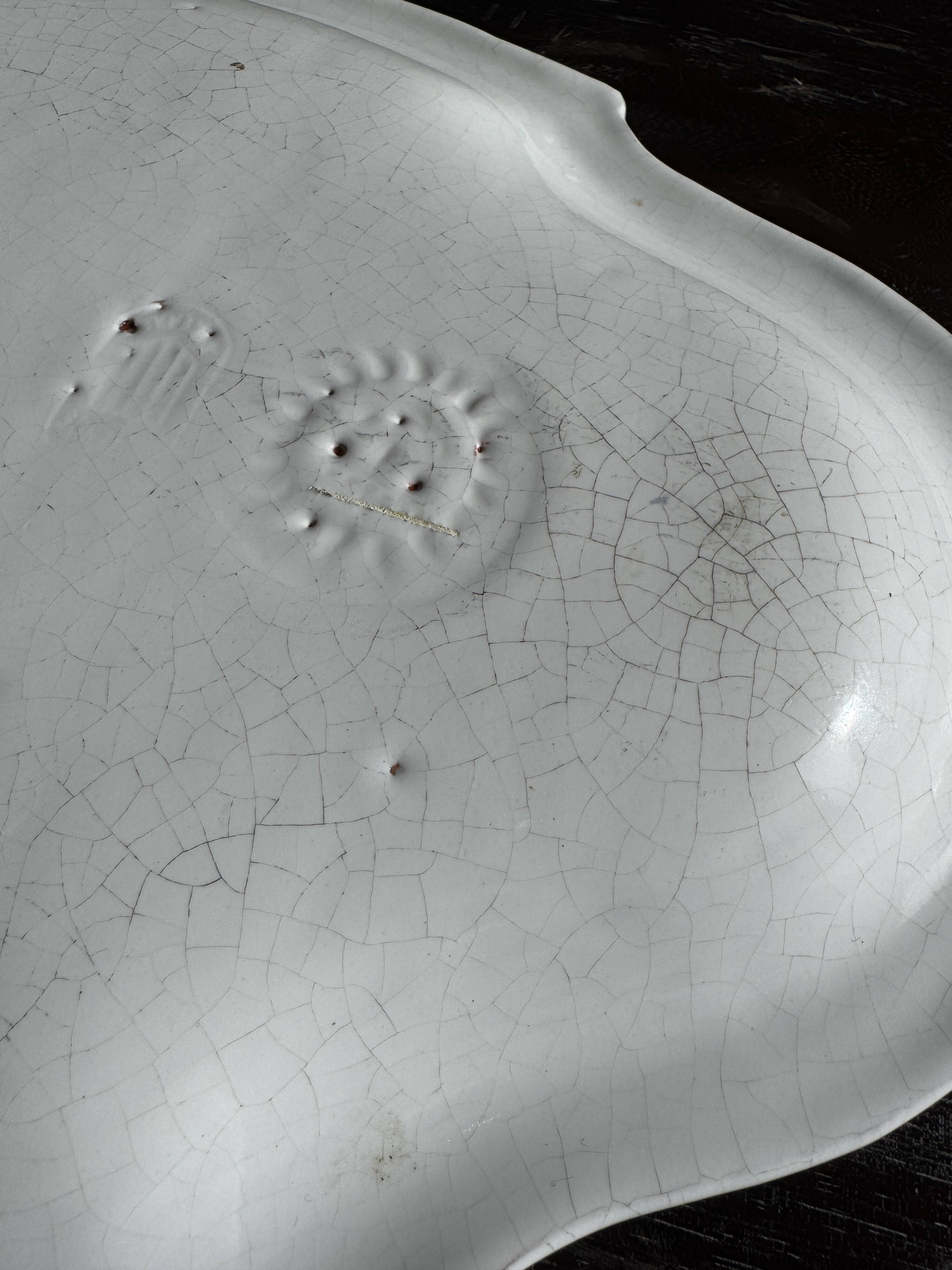 Antique oval-shaped white crackled faience plate with a scalloped edge.
