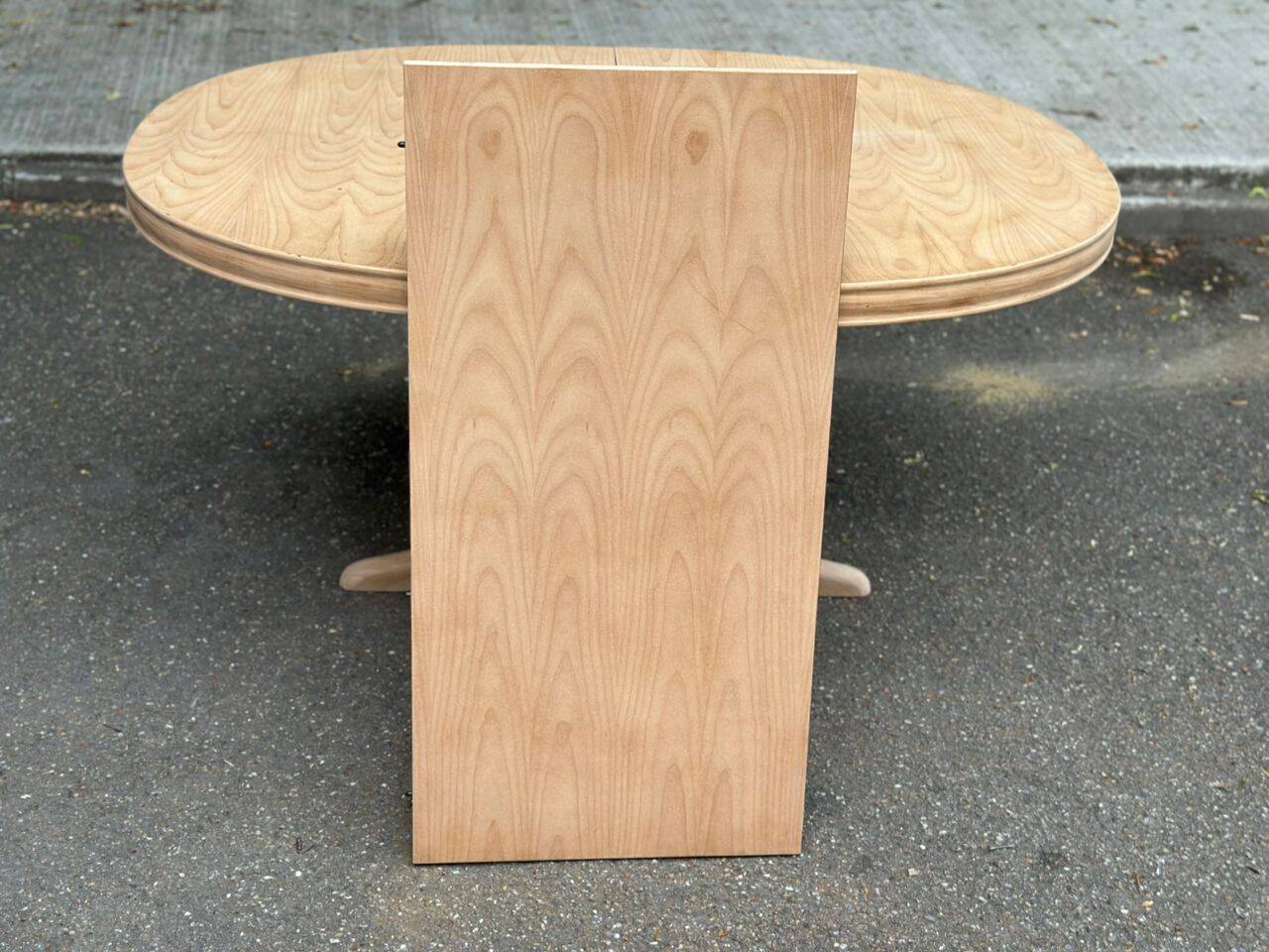 Renovated oval Scandinavian extendable dining table in wood with a central leg.