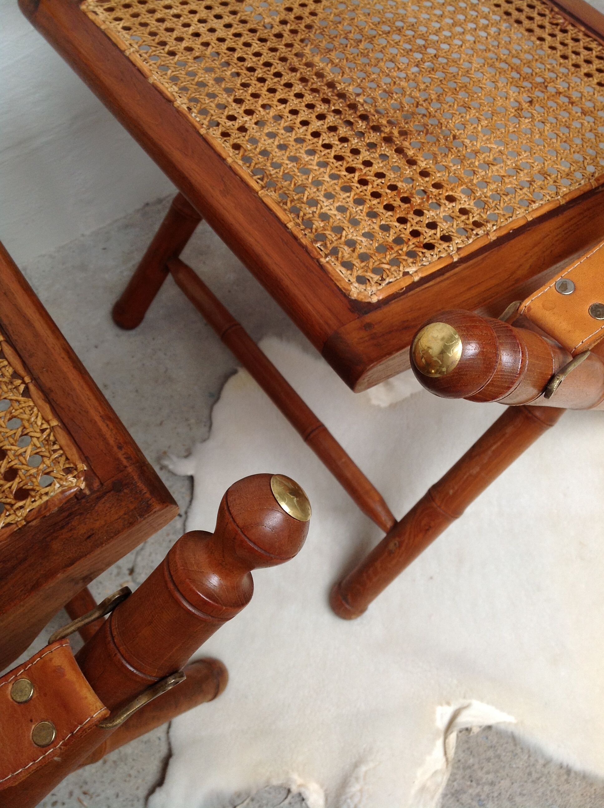 Pair of folding chairs in bamboo and caning, leather and brass
