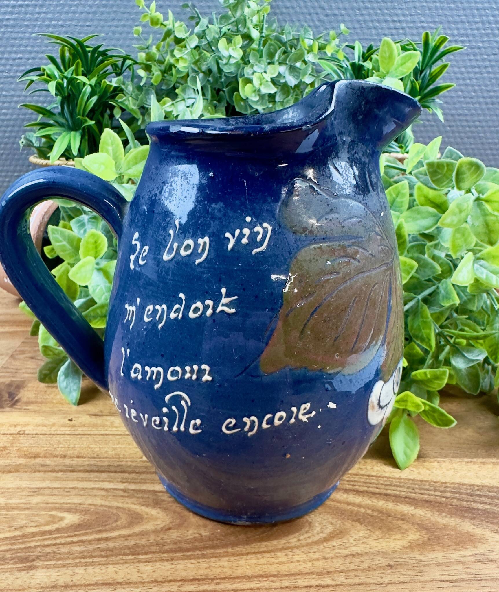 Blue ceramic pitcher with vintage artisan inscription decoration.