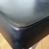 Chrome metal chairs and black faux leather upholstery in retro modernist style.