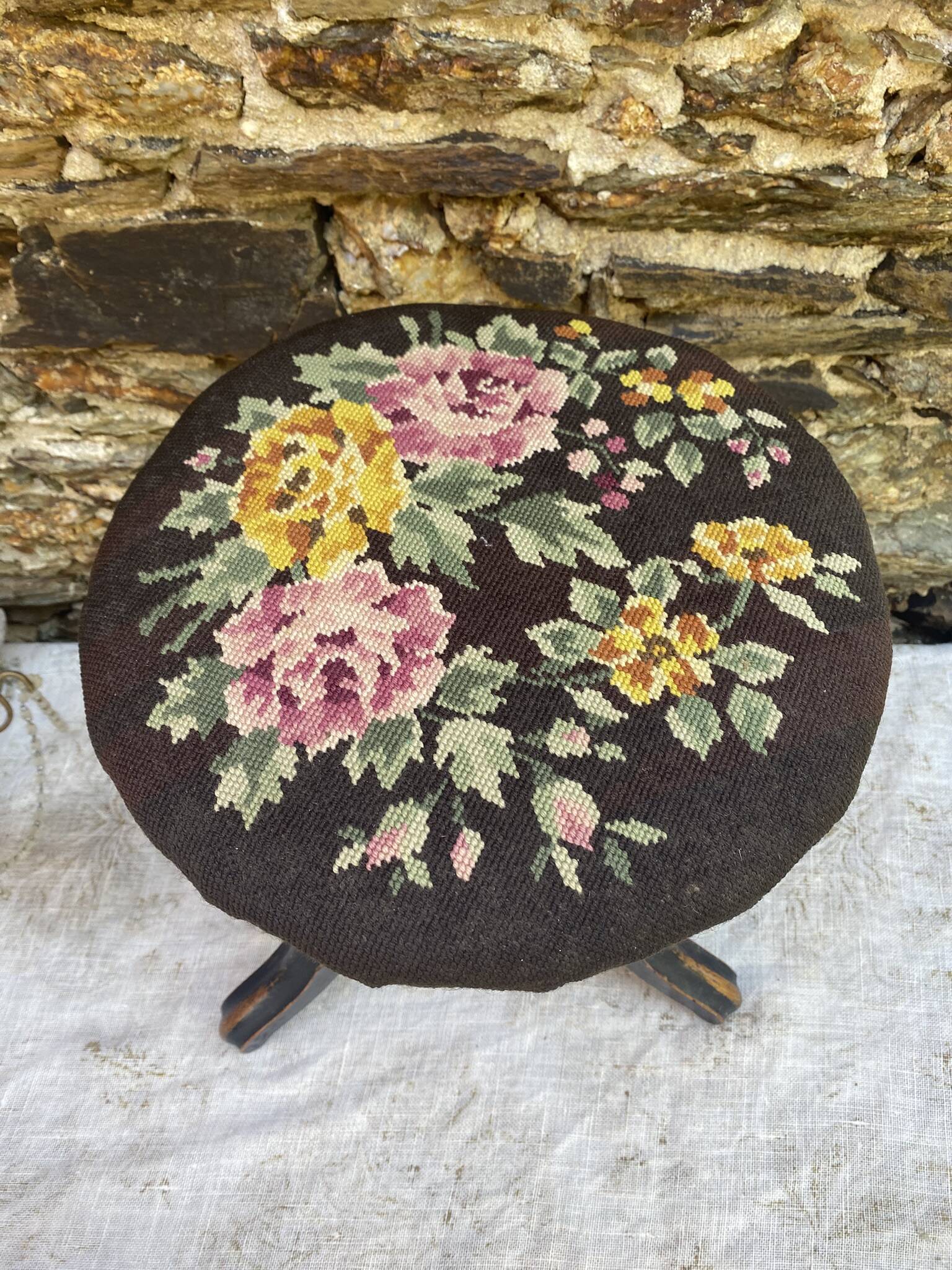Old adjustable piano stool, blackened wood, metal screws, embroidered seat.