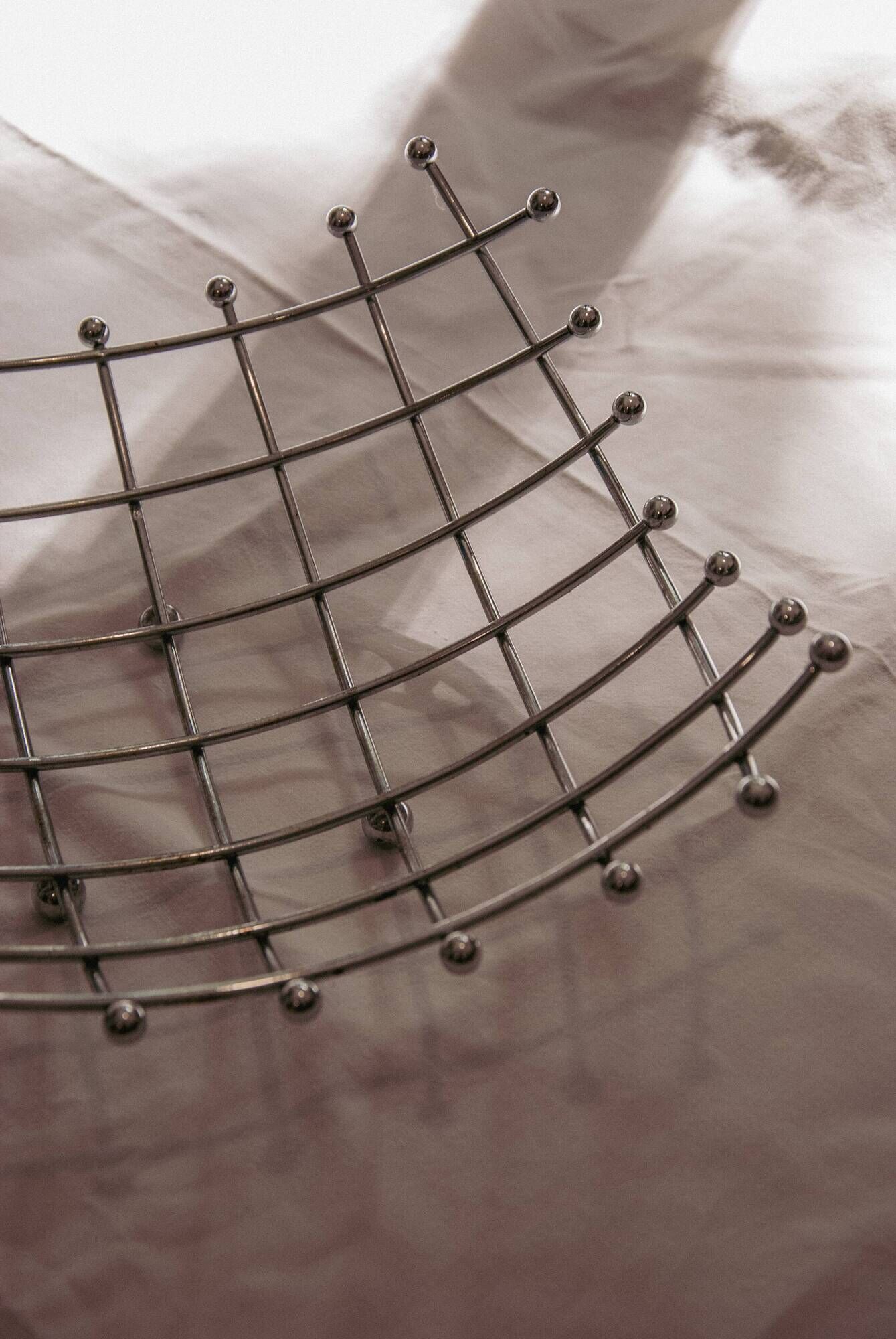 Curved grid fruit bowl, chrome metal and beads.